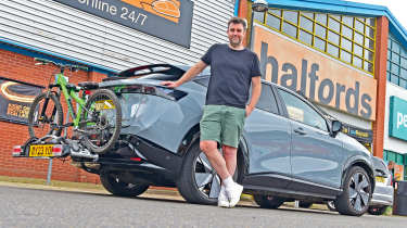 Auto Express head of digital content Steve Walker standing next to the Nissan Ariya outside a branch of Halfords