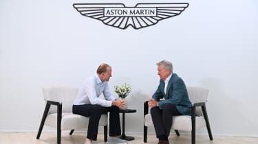 Aston CEO Adrian Hallmark talking to Phil McNamara under logo