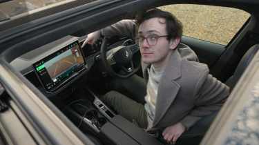 Auto Express consumer editor Tom Jervis sitting in a Volkswagen Passat and looking through the open sunroof 