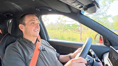 Thomas Geiger standing driving the Genesis GV60 Magma