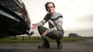 Auto Express consumer editor Tom Jervis pointing at a Volkswagen Passat's towbar