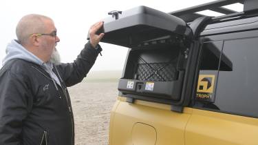 Auto Express senior test editor Dean Gibson inspecting the Land Rover Defender 110 Trophy Edition's exterior storage box