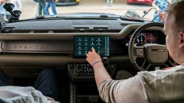 Auto Express news reporter Ellis Hyde operating the Land Rover Defender OCTA&#039;s infotainment sytem