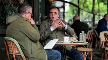 Dacia CEO Denis Le Vot and John McIlroy sitting outside a French cafe