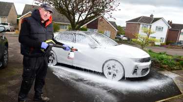 Auto Express products editor Kim Adams standing next to the snowfoam-covered Vauxhall Astra GSe