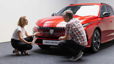 Auto Express editor Paul Barker crouching in front of the facelifted Peugeot 308