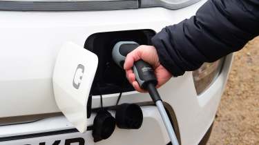 Person plugging a charger into a Kia Soul EV