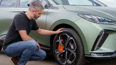 Carbuyer and DrivingElectric editor Richard Ingram inspecting the MG4 XPower&#039;s front offside wheel