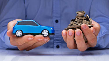 Hand holding a model car and a stack of coins